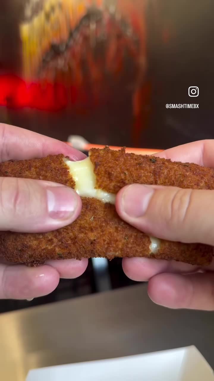 A mozzarella stick pulled apart showing a long cheese pull