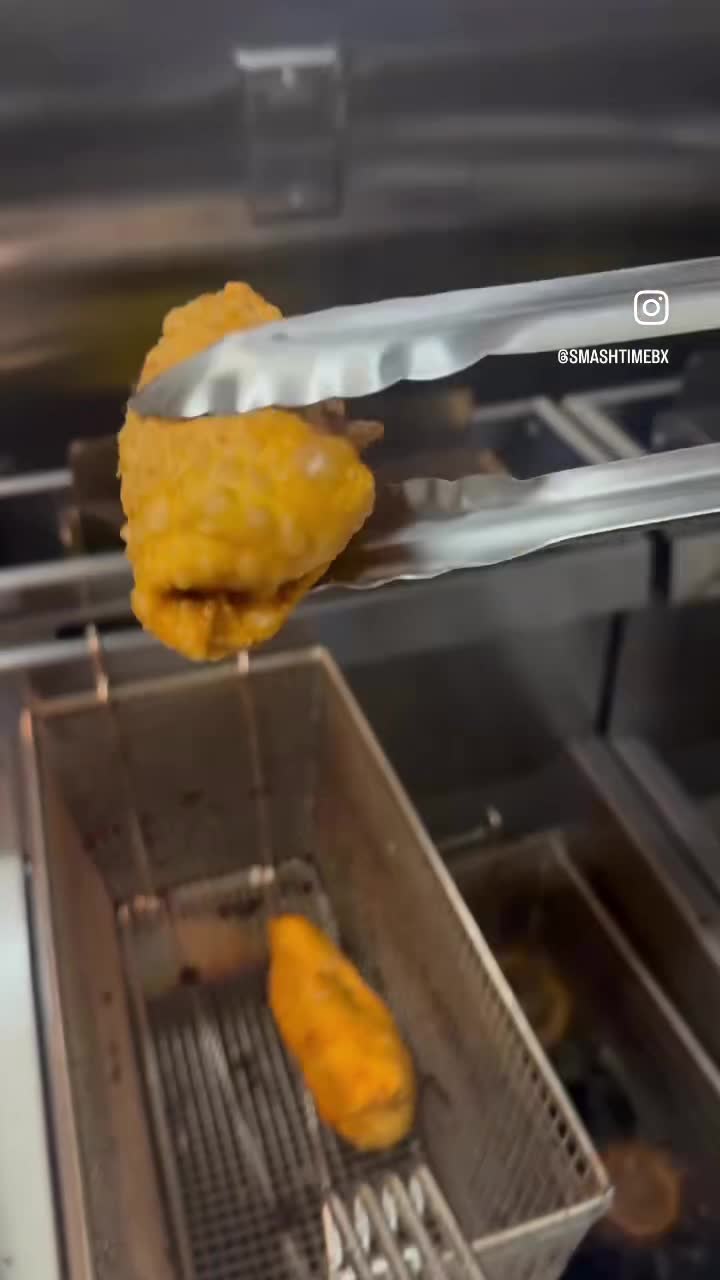 An egg roll lifted out of the fryer with tongs